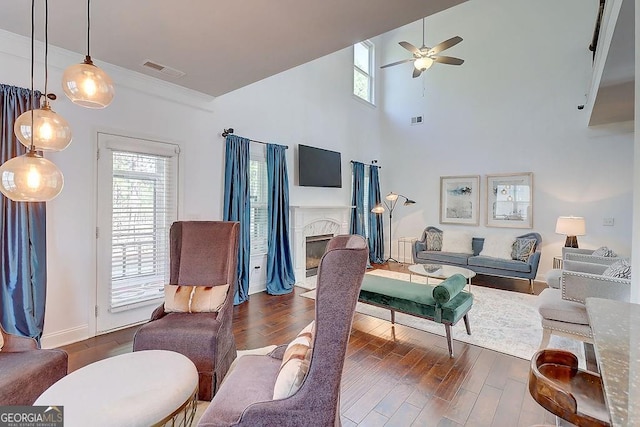 living area with plenty of natural light, visible vents, a fireplace, and wood finished floors