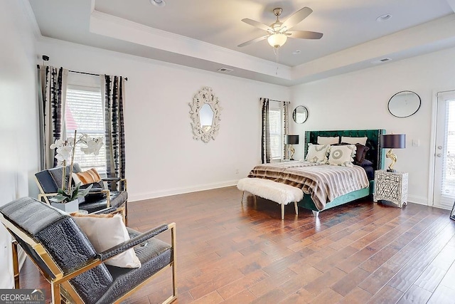 bedroom featuring baseboards, a raised ceiling, and wood finished floors