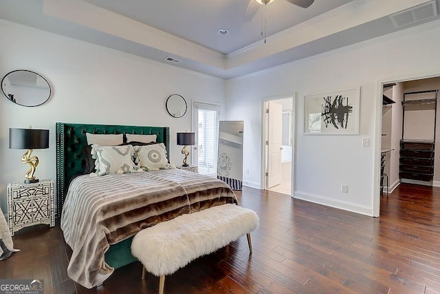 bedroom with wood-type flooring, a raised ceiling, and visible vents