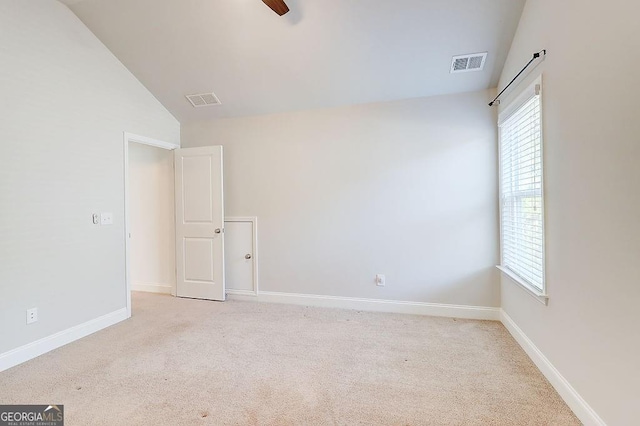 carpeted empty room with vaulted ceiling, ceiling fan, visible vents, and baseboards