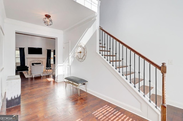 entryway featuring wood-type flooring, stairway, baseboards, and ornamental molding