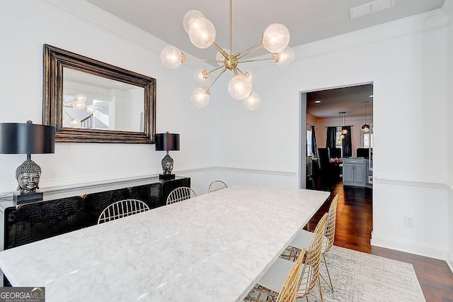 dining room with crown molding, visible vents, a chandelier, and dark wood-style flooring