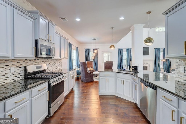 kitchen featuring decorative light fixtures, dark wood finished floors, stainless steel appliances, tasteful backsplash, and dark stone counters