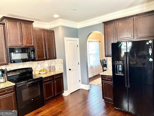 kitchen with tasteful backsplash, arched walkways, dark wood finished floors, light stone countertops, and black appliances