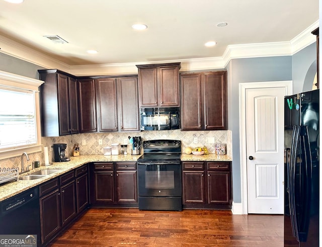 kitchen featuring ornamental molding, dark wood-style flooring, light stone countertops, black appliances, and a sink