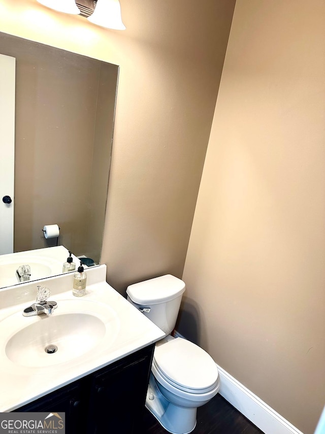 bathroom featuring baseboards, vanity, and toilet