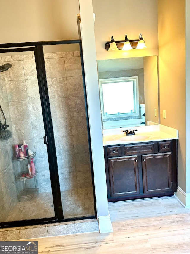 full bath with a stall shower, wood finished floors, and vanity