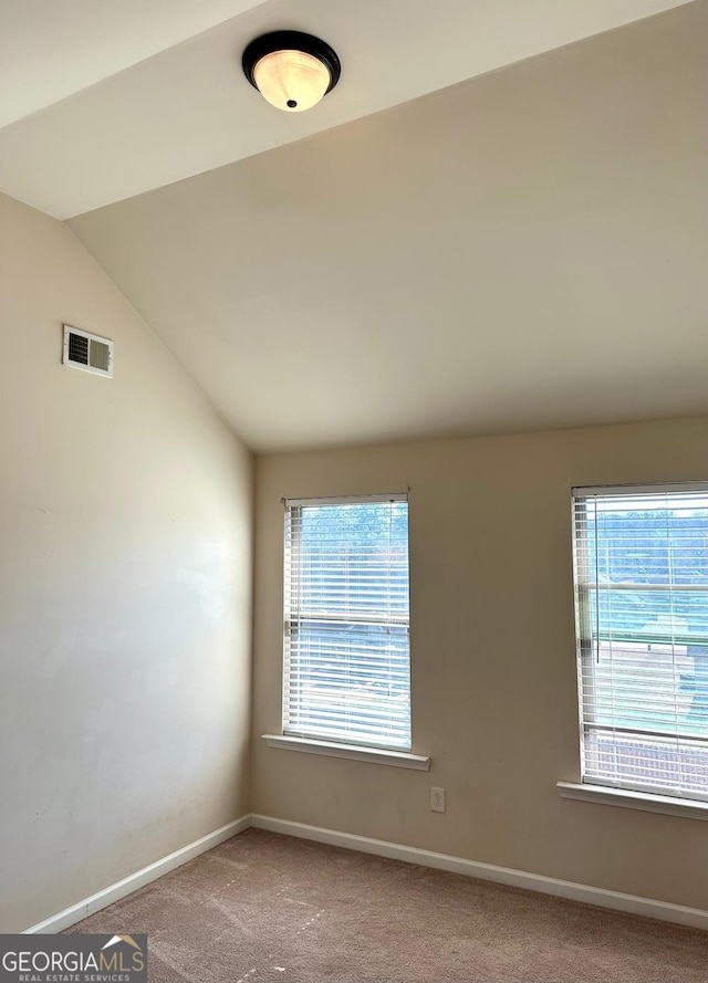 unfurnished room featuring lofted ceiling, carpet floors, visible vents, and baseboards