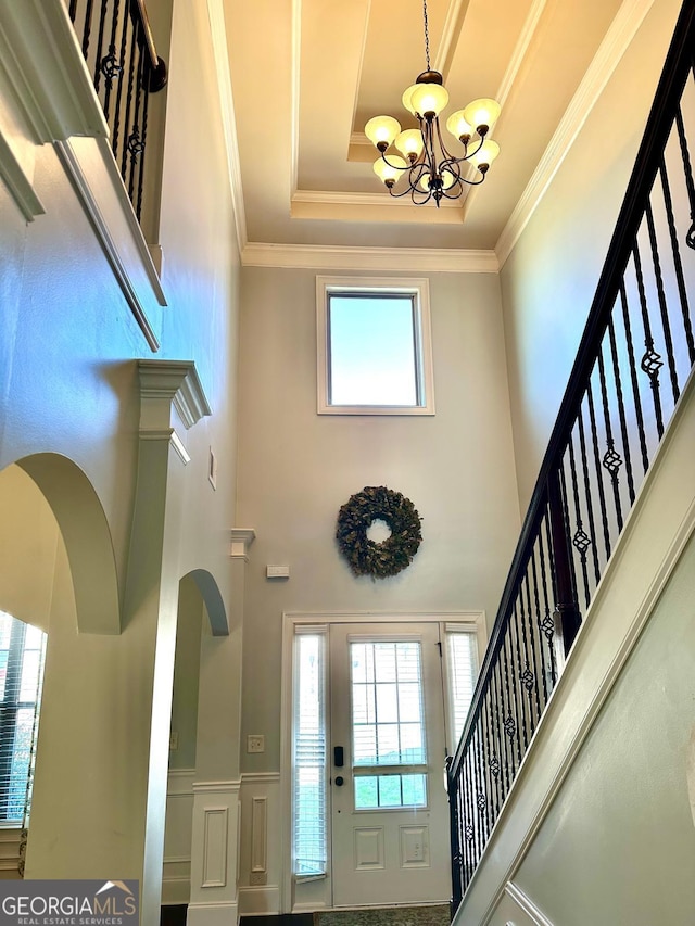 entryway featuring a decorative wall, ornamental molding, a chandelier, and wainscoting