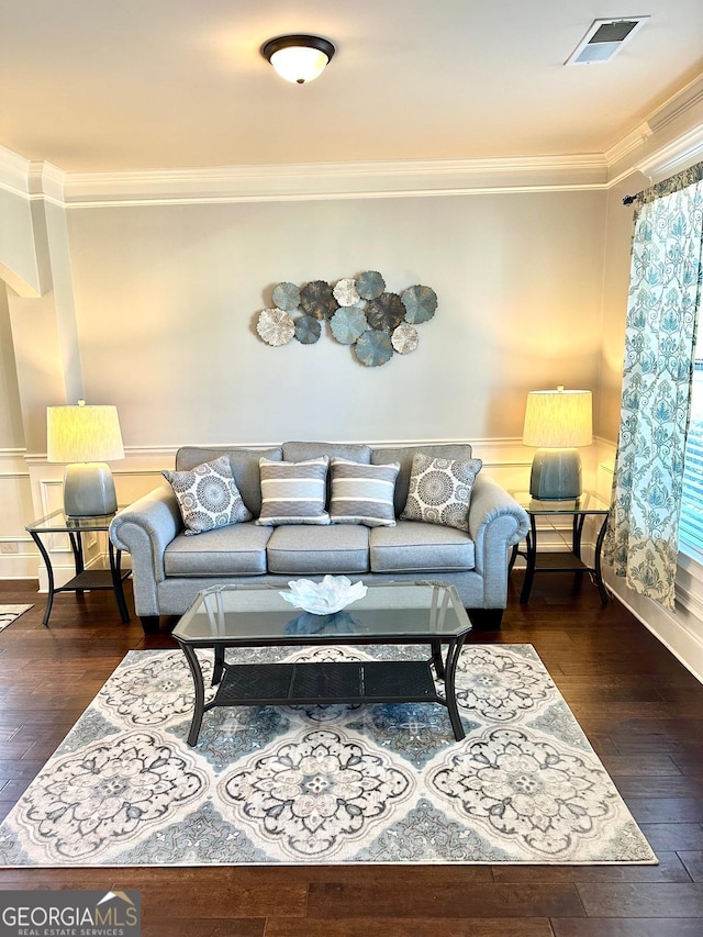 living room with crown molding, visible vents, hardwood / wood-style floors, and wainscoting