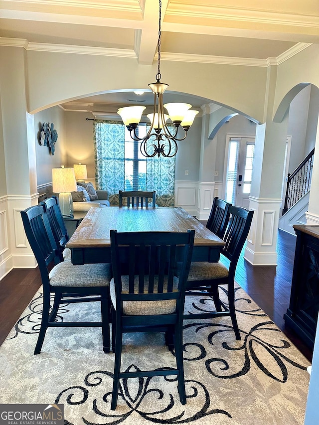 dining area featuring stairs, arched walkways, wainscoting, and wood finished floors