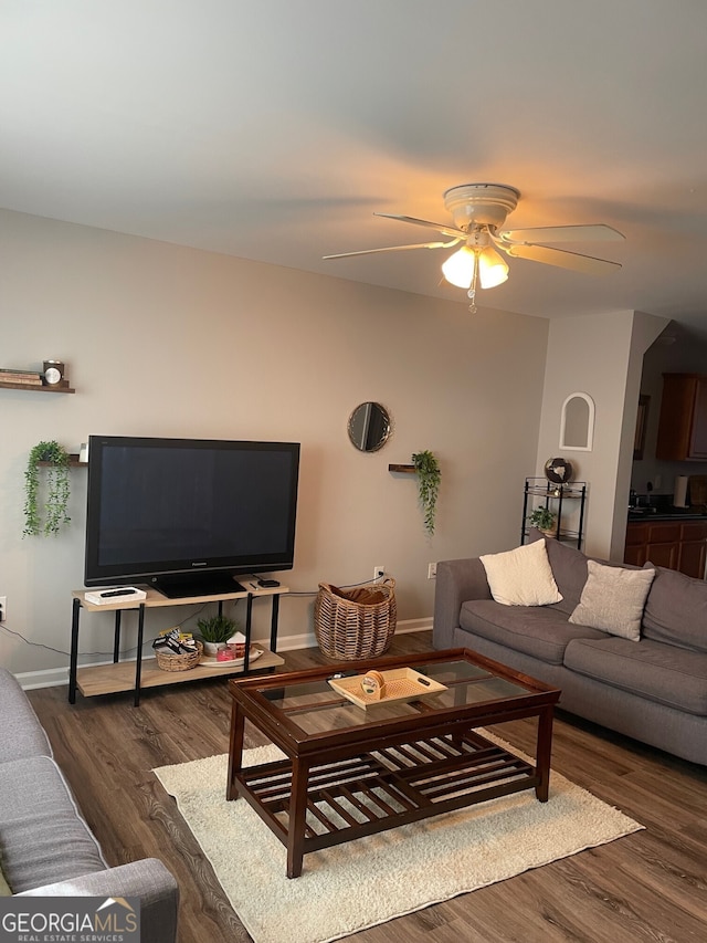 living room with ceiling fan, baseboards, and wood finished floors