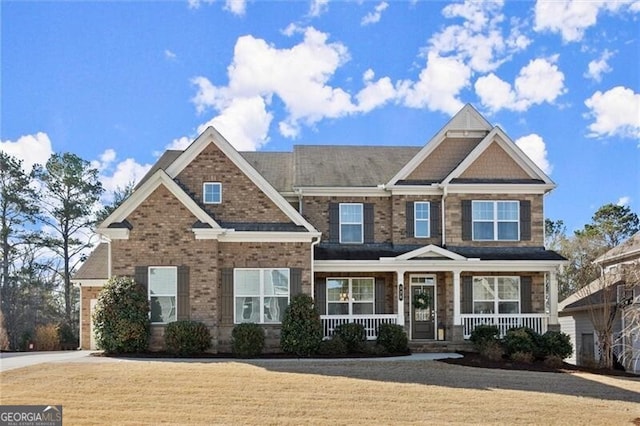 craftsman-style home with a front lawn, a porch, and brick siding