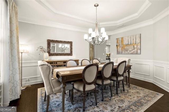 dining space featuring a raised ceiling, a notable chandelier, a decorative wall, and dark wood-style flooring