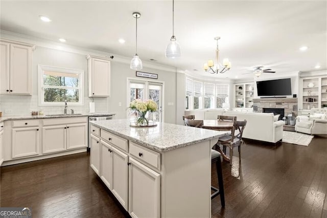 kitchen with dark wood-style floors, a fireplace, a sink, and dishwasher