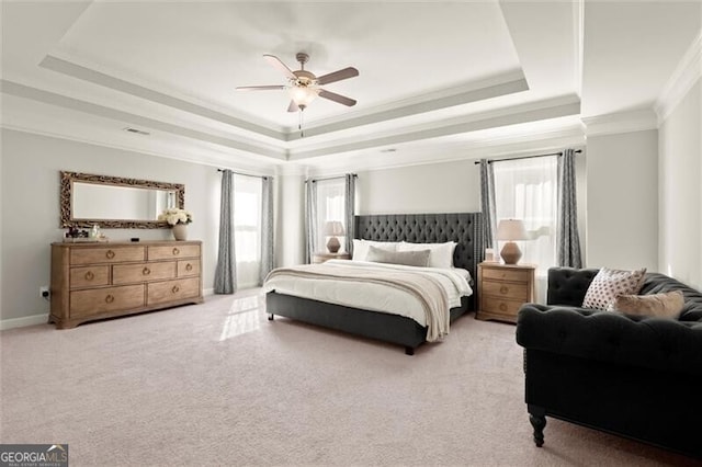 bedroom with ornamental molding, a tray ceiling, multiple windows, and light colored carpet