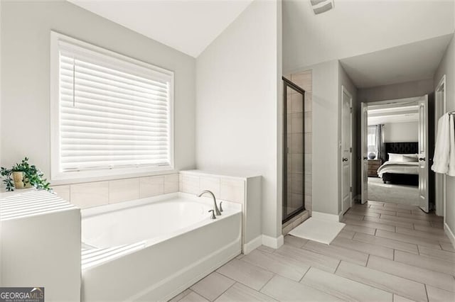 ensuite bathroom featuring a stall shower, a garden tub, lofted ceiling, and ensuite bath