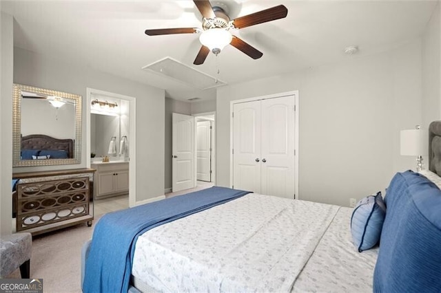 bedroom featuring a closet, attic access, light carpet, ceiling fan, and ensuite bath