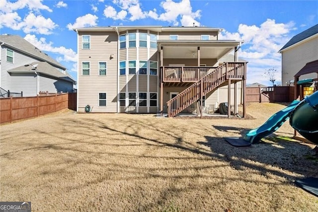 back of house featuring a lawn, a fenced backyard, stairs, a wooden deck, and a playground