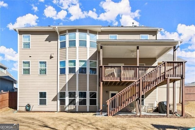 rear view of property with fence, a wooden deck, and stairs