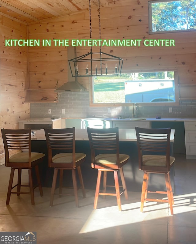 kitchen featuring a kitchen bar, wooden ceiling, backsplash, and a sink