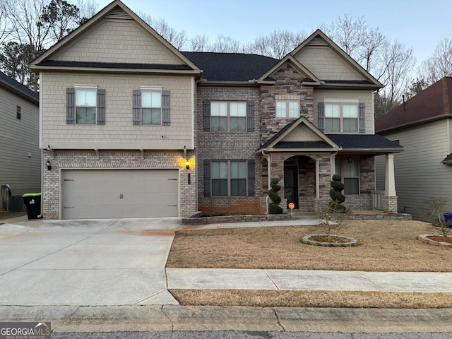 view of front of home featuring a garage, driveway, brick siding, and stone siding