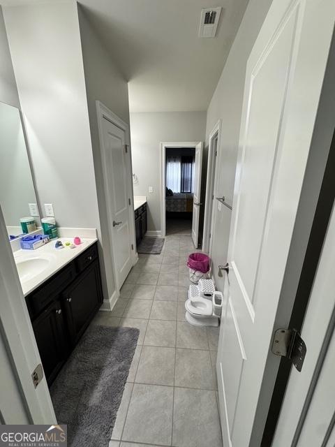 bathroom featuring tile patterned flooring, visible vents, baseboards, and vanity