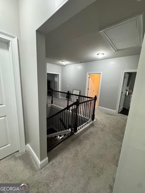 corridor with carpet floors, attic access, baseboards, and an upstairs landing