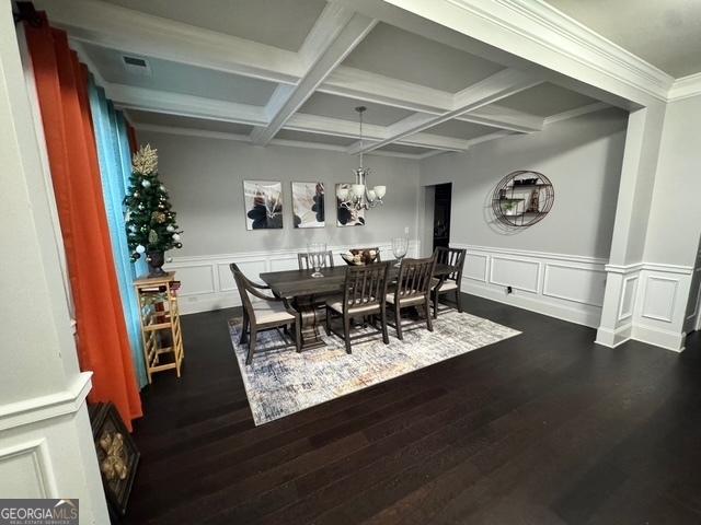 dining room with a chandelier, a decorative wall, dark wood-type flooring, coffered ceiling, and beamed ceiling