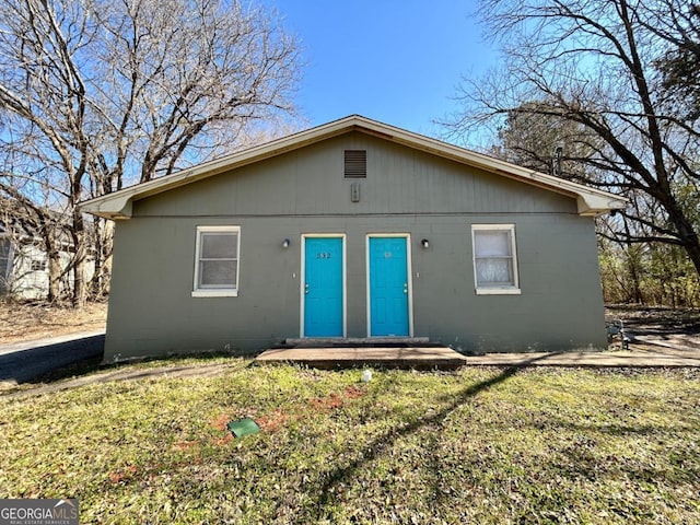 rear view of house featuring concrete block siding and a yard