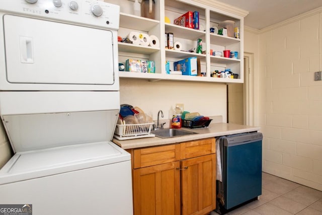 laundry room with ornamental molding, stacked washing maching and dryer, a sink, and light tile patterned flooring