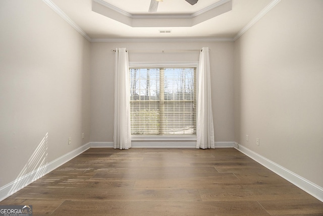 spare room featuring visible vents, a tray ceiling, and wood finished floors