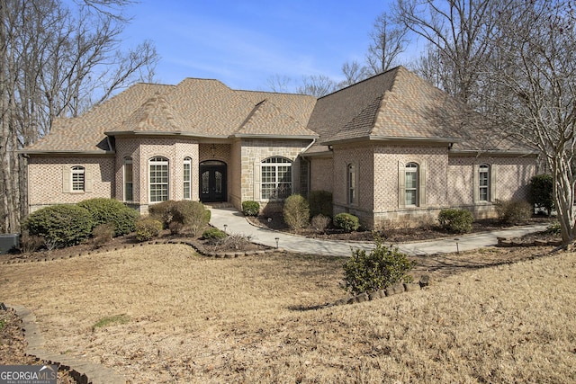 french country home featuring brick siding