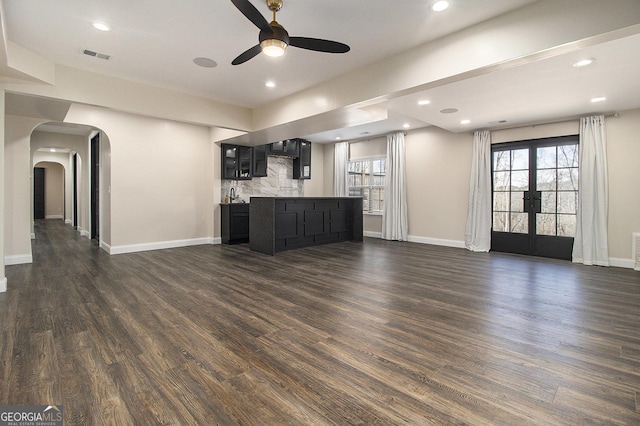 kitchen featuring open floor plan, arched walkways, visible vents, and dark cabinets