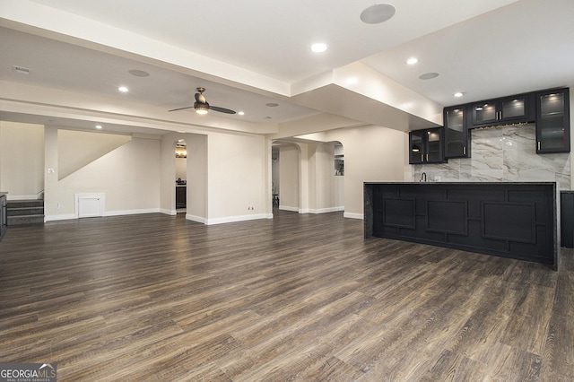 unfurnished living room with dark wood-style floors, ceiling fan, stairs, and baseboards