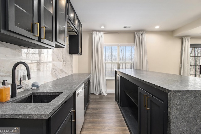 kitchen featuring dark cabinetry, dark countertops, and a sink