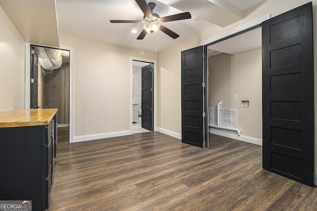 unfurnished bedroom with ensuite bathroom, dark wood-style flooring, and baseboards