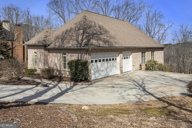 view of side of home featuring an attached garage, concrete driveway, and brick siding