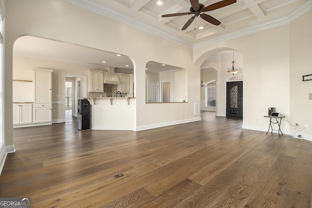 unfurnished living room featuring dark wood-type flooring, arched walkways, coffered ceiling, and a towering ceiling