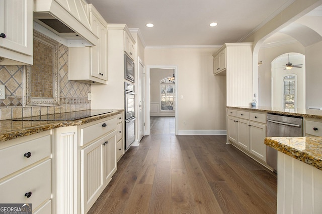 kitchen featuring stone countertops, arched walkways, ornamental molding, appliances with stainless steel finishes, and premium range hood