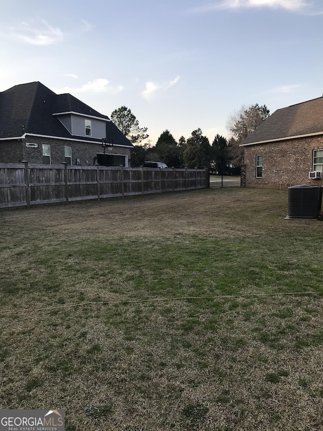 view of yard with central AC and fence