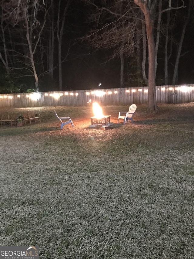 view of yard featuring an outdoor fire pit, a water view, and fence