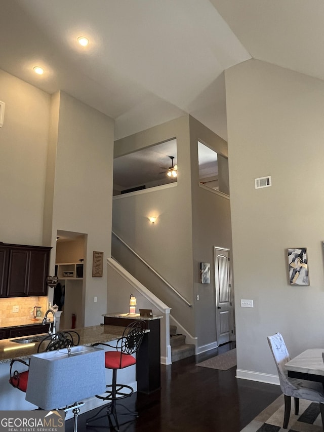 kitchen with high vaulted ceiling, visible vents, a sink, and decorative backsplash