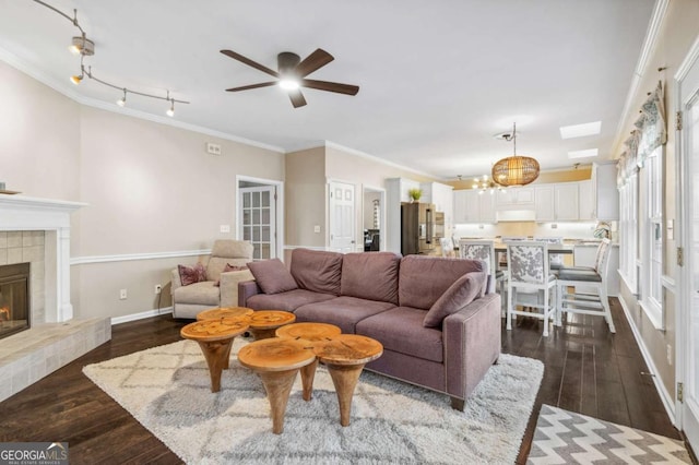 living area with ornamental molding, a fireplace, dark wood finished floors, and baseboards