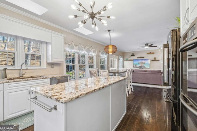 kitchen with a kitchen island, ornamental molding, open floor plan, and a sink