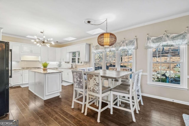 dining room with crown molding, a skylight, dark wood finished floors, and baseboards