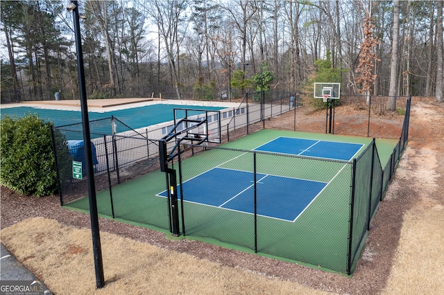 view of basketball court featuring a tennis court, community basketball court, and fence