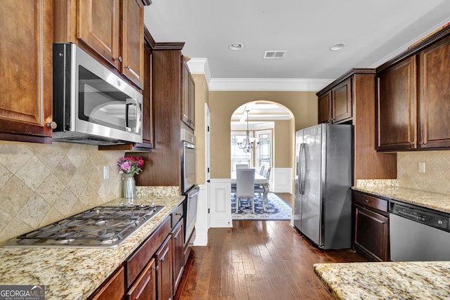 kitchen with arched walkways, visible vents, appliances with stainless steel finishes, wainscoting, and crown molding