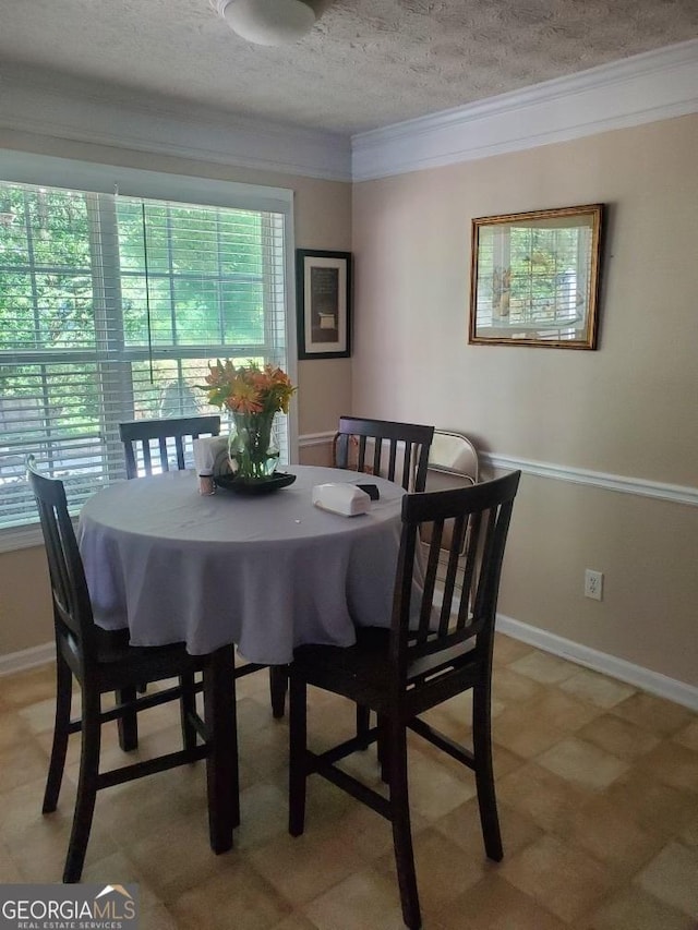 dining area with a textured ceiling, ornamental molding, and baseboards