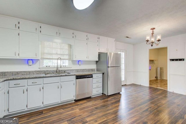 kitchen featuring dark wood-style floors, stainless steel appliances, white cabinets, a sink, and a textured ceiling